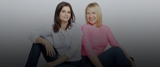 zwei sportliche frauen sitzen ruecken an ruecken pilatestrainerinnen wer sind wir